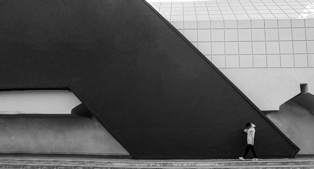 A person walks past a dark, angled building.