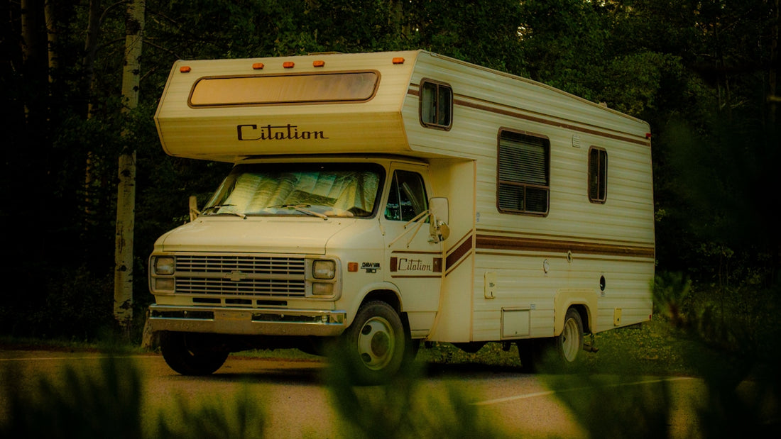 White rv parked on a dirt road surrounded by trees