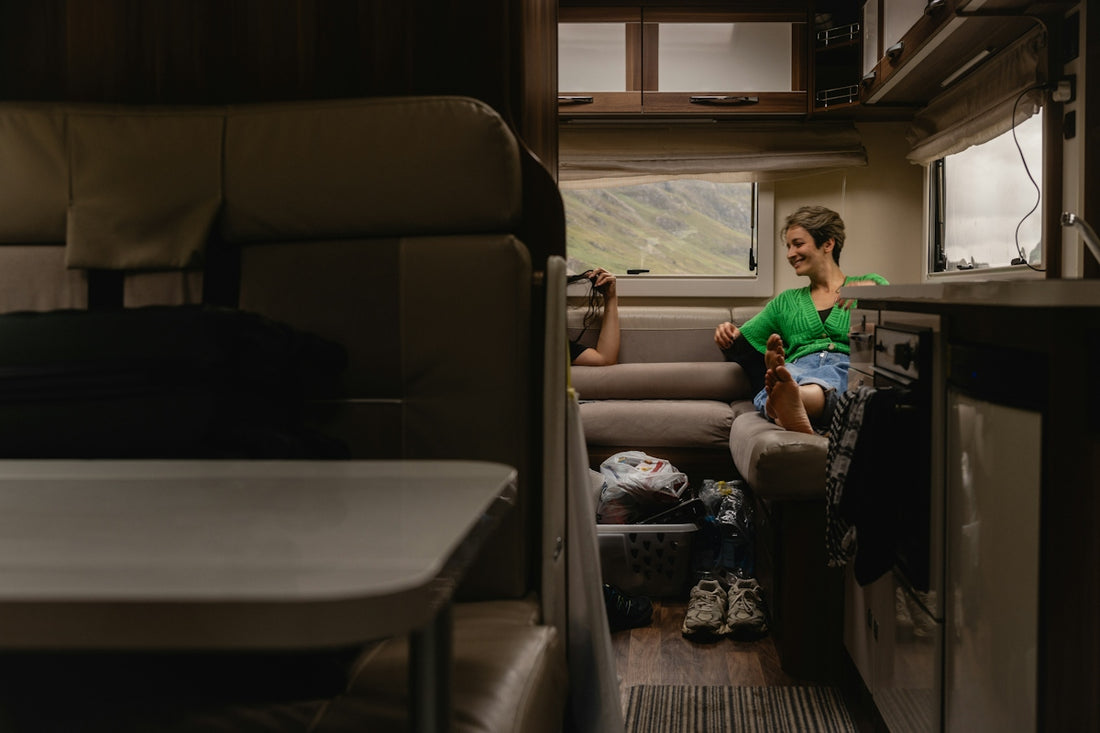 A woman in a green cardigan relaxing on a camper van sofa